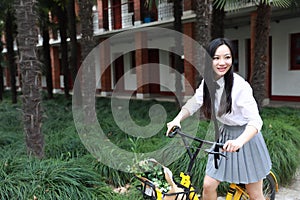 Happy cute lovely beautiful young girl high school college student enjoy free time ride a bike at school