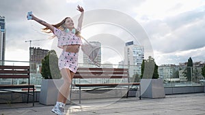 Happy cute millenial hipster girl having fun outdoor at city streets urban background. Beauty woman spinning, jumping