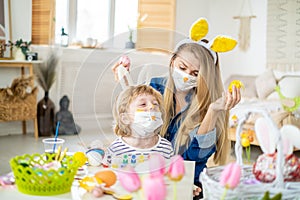 Happy cute mother and son wearing decorated bunny face mask and headbands with ears having fun getting ready for Easter