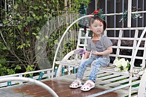 Happy cute naughty lovely adorable little girl play lolipop and sit on a carriage have fun outdoor in summer park