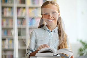 Happy cute schoolchild standing at a desk with books