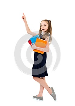 Happy cute smiling cheerful child girl in school uniform holding books and pointing up. Schoolgirl with facial expression isolated