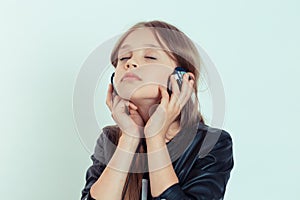 Happy cute smiling kid girl listening to music in her headphones