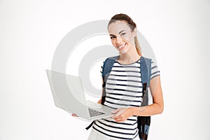 Happy cute student girl with backpack standing and holding laptop