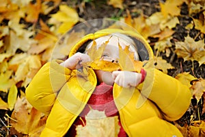 Happy cute toddler boy having fun with autumn leaves