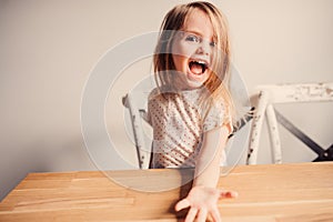 Happy cute toddler girl playing at home in kitchen