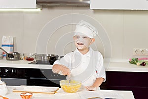 Happy cute young boy baking in the kitchen