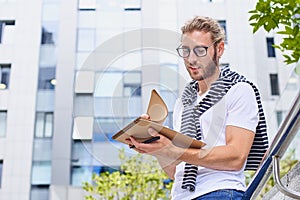 Happy cute young man with an album for drawing in an urban setting