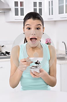 Happy cute young woman eats a cake photo