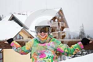 Happy cute young woman in helmet, glasses and a bright jacket at the ski resort