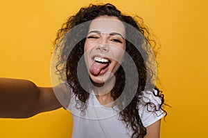 Happy cute young woman posing isolated over yellow background take a selfie by camera.