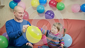Happy dad and daughter inflate balloons and play. Concept of holiday, birthday