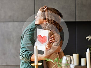 Happy dad getting congratulations from his cute daughter on Fathers day, holding greeting postcard