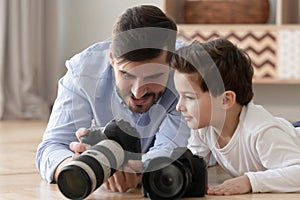 Happy dad and kid son play digital cameras at home