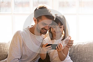 Happy dad and little child girl holding phone using smartphone