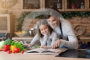 Happy dad and little daughter checking recipe in cookbook together