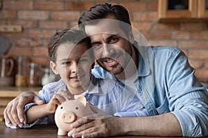 Happy dad and little son holding piggy bank, smiling