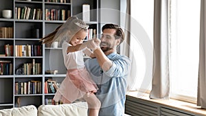 Happy dad and preschooler daughter dance have fun at home