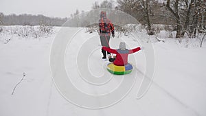 Happy dad sledges a child on a snowy road. Christmas Holidays. father plays with his daughter in a winter park. The