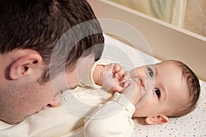Happy dad and son having fun at home. Father and baby boy in bedroom on a bright background. Tenderness, parenthood