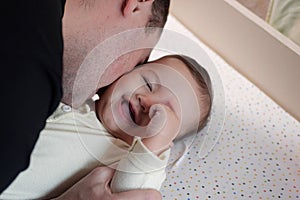 Happy dad and son having fun at home. Father and baby boy in bedroom on a bright background. Tenderness, parenthood