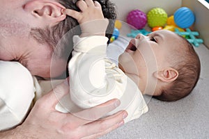 Happy dad and son having fun at home. Father and baby boy in bedroom on a bright background. Tenderness, parenthood