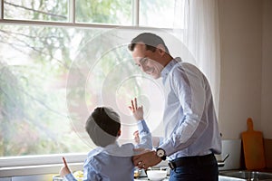 Happy dad and son having fun in kitchen together