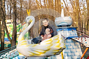 Happy dad and son ride on attractions in a city park on a sunny day.