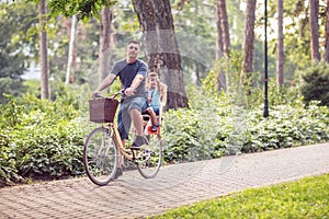 Happy Dad and son riding bicycles outdoors in a city park