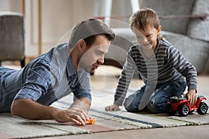 Happy dad and son wheeling toy cars on heat floor