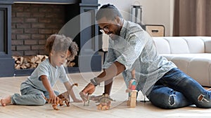 Happy daddy and toddler son playing games with small dinosaurs