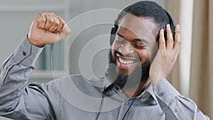 Happy dancing at office African American man worker ethnic businessman manager entrepreneur executive in headphones