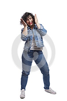 Happy dancing young girl in jeans. Positive and happy. Bright brunette with curly hair and red lipstick. Isolated on a white