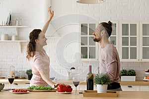 Happy dating couple having fun while cooking in home kitchen