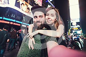 Happy dating couple in love taking selfie photo on Times Square in New York while travel in USA on honeymoon