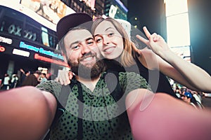 Happy dating couple in love taking selfie photo on Times Square in New York while travel in USA on honeymoon