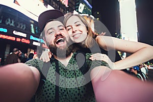 Happy dating couple in love taking selfie photo on Times Square in New York while travel in USA on honeymoon