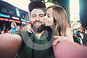 Happy dating couple in love taking selfie photo on Times Square in New York while travel in USA on honeymoon