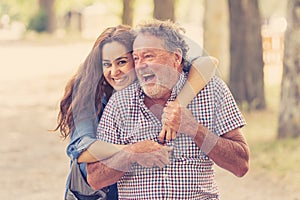 Happy daughter embracing her senior father from back in the park