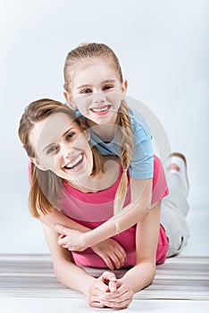 Happy daughter hugging laughing mother on white