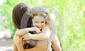 Happy daughter hugging mother in warm sunny summer day on the nature