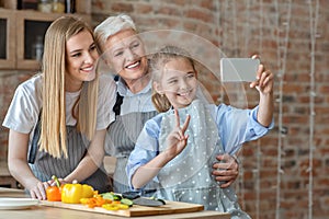 Happy daughter, mother and grandmother taking selfie while cooking together