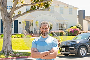 happy dealer man standing next to the car and new house