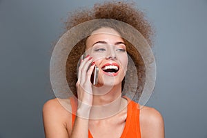 Happy delightful curly woman talking on mobile phone and laughing