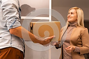 Happy deliverer carrying packages while making home delivery to his customer.