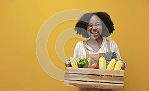 Happy delivery from African American woman carrying cart full of tropical organic homegrown produce from local garden for vegan