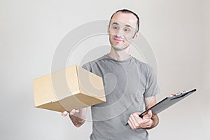 Happy delivery man with gray t-shirt carrying a parcel box on a white background