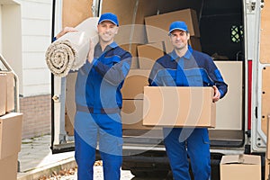 Happy Delivery Men Carrying Cardboard Box And Carpet