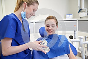 Happy dentist showing jaw model to patient girl