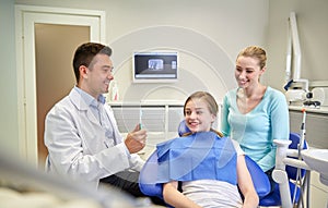 Happy dentist showing toothbrush to patient girl